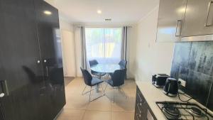 a kitchen with a table and chairs in a kitchen at Timeless Tranquility in Belconnen +3 photos