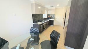 a kitchen with a glass table and black chairs at Timeless Tranquility in Belconnen