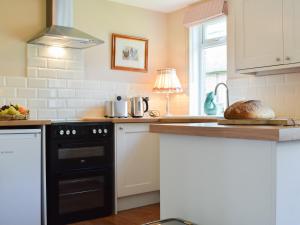 Il comprend une cuisine équipée d'une cuisinière noire et d'un évier. dans l'établissement Club Cottage, à Dummer