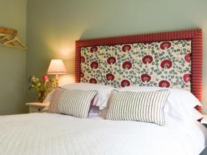 - une chambre avec un lit blanc et une tête de lit fleurie dans l'établissement Club Cottage, à Dummer