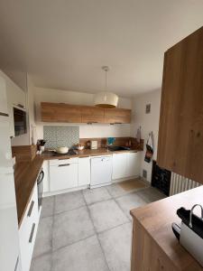a large kitchen with white cabinets and a ceiling at Entre Lac, Fleurs et Montagnes in Thonon-les-Bains