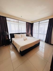 a bedroom with a large bed in a room with windows at Times Square KL Serviced Suite in Kuala Lumpur