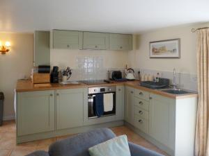a kitchen with green cabinets and a stove top oven at Wren Cottage in Netherbury