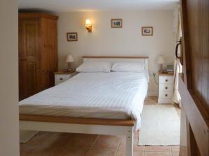 a bedroom with a white bed and two night stands at Wren Cottage in Netherbury