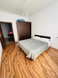a bedroom with a bed and a wooden floor at Ovidius apartament in Cisnădie