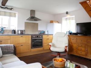 eine Küche mit Holzschränken und einem weißen Stuhl in der Unterkunft Stable Cottage in Icklesham