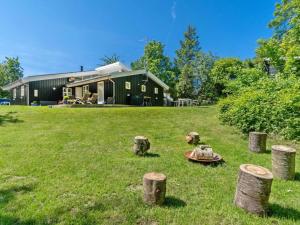 a green yard with a house and some logs at 8 person holiday home in Græsted-By Traum in Udsholt Sand +28 photos