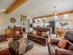 a living room with leather furniture and a kitchen at Briar Cottage in Great Eccleston