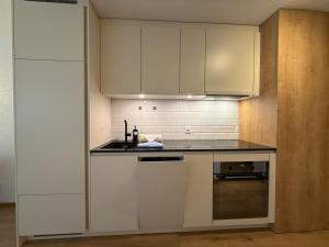 cocina con armarios blancos y encimera en Rothornblick 32 by Arosa Holiday, en Arosa