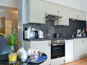 a kitchen with white cabinets and a table with food at Caddys Cottage - Uk6714 in Lydstep
