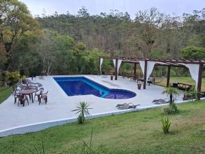 a swimming pool in a yard with a table and chairs at Chale Rio Nascente in Salesópolis