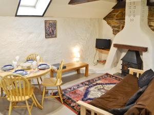 Una sala de estar con una mesa y una chimenea. en The Old Stable, en Holywell Bay