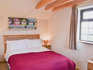 Un dormitorio con una cama con una manta roja. en The Old Stable, en Holywell Bay