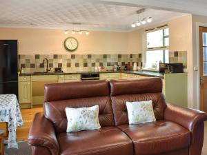 sala de estar con sofá de cuero marrón en la cocina en The Granary - Uk47428, en Bewaldeth