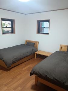 zwei Betten in einem Zimmer mit zwei Fenstern in der Unterkunft 草津温泉お宿きみのや in Kusatsu