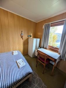 una habitación con una cama, una mesa y un refrigerador en Room at House of ade, en Senja