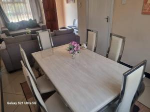 a dining room table with a vase of flowers on it at Luta Serviced Apartment in Lusaka