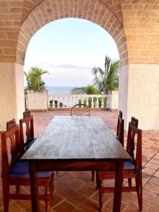 une table et des chaises en bois sur une terrasse avec l'océan dans l'établissement Beachfront Villa, Bofa Rd Kilifi, à Kilifi