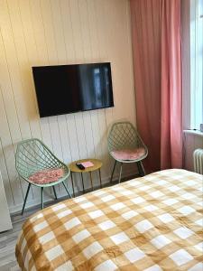 a bedroom with two chairs and a tv on the wall at Cityinn Apartments in Viborg