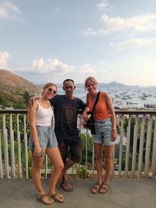 a man and two women standing on a balcony at PENDIK Home Stay in Labuan Bajo