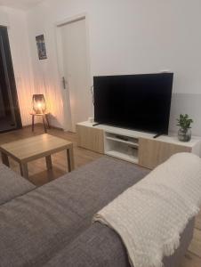 Una sala de estar con un televisor de pantalla plana en un centro de entretenimiento. en Séjour cosy avec vue mer, Clim et Netflix, en La Ciotat