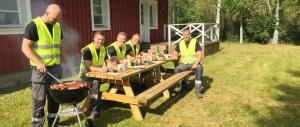 a group of men in yellow vests sitting at a picnic table at Spacious Cabin for Work Crews, 10 Beds! in Ingelstad