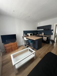 een woonkamer met een witte salontafel en een keuken bij Confort appart in Oyonnax
