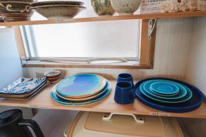 a shelf with plates and cups and dishes on it at Haruhiya in Ishigaki Island