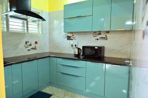 a kitchen with blue cabinets and a microwave at Suhas Nest in Mysore