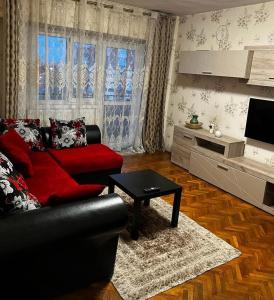a living room with a red couch and a table at Exquisit Apartament in Buzau