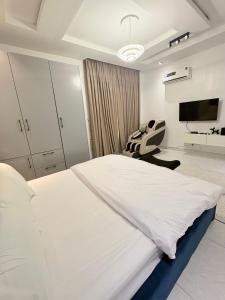 a white bedroom with a large bed and a tv at One bedroom apartment with massage chair and PS5 in Lagos +1 photo