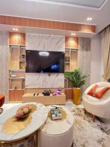 Una sala de estar con un televisor grande y una mesa. en Bethaven, en Lekki