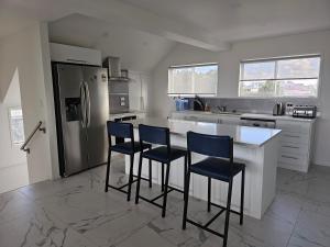 a kitchen with a refrigerator and three bar stools at Pyramid beach house in Karikari Peninsula