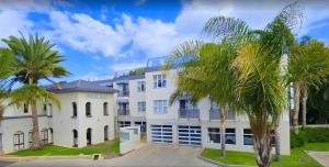 Un edificio blanco con palmeras delante. en Luxury Villa at Riviera Hotel Hartenbos, en Mossel Bay
