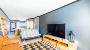 Una sala de estar con un televisor de pantalla plana grande en una pared. en Luxury Villa at Riviera Hotel Hartenbos, en Mossel Bay