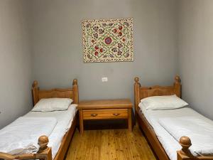Dos camas en una habitación con un cuadro en la pared. en NURATA MOUNTAIN GUESTHOUSE Shiringul, en Yukary-Ukhum