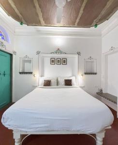 a white bedroom with a large white bed at Little Garden Guest House in Udaipur