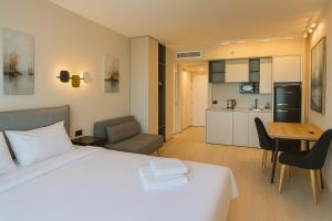 a bedroom with a white bed and a kitchen at Sea Breeze Apartments in Netanya