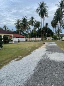 a gravel road in front of a building with palm trees at DamaiSari Tawang in Bachok