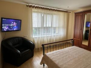 a bedroom with a bed and a chair and a television at Venta City Apartment in Venta