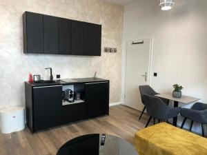 a kitchen with black cabinets and a table with chairs at Aura Apartament Oberhausen in Oberhausen