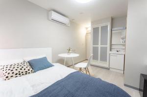 Un dormitorio blanco con una cama y una mesa. en 9stay蔵前, en Tokio