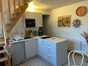 a kitchen with white cabinets and a staircase with a clock at Côté Poules in Quesnoy-sur-Airaines
