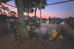 a table and chairs on a balcony with a sunset at Beachside Modern Wellness at Jupiter Bay Resort in Jupiter