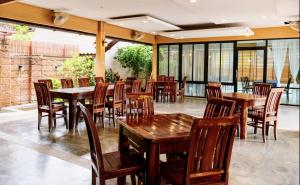 a restaurant with wooden tables and chairs and windows at The Nine Bed & Restaurant in Ban Don Rak