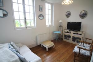 a living room with a couch and a tv at le gîte de Claire maison avec terrasse, calme et confort, lit king size linge fourni in Couze-et-Saint-Front