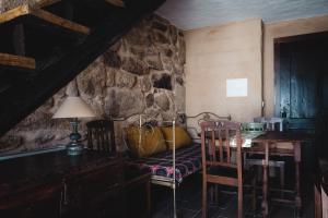 a room with a table and chairs and a stone wall at Casa dos Candeias - Apartamento Tio João in Chaves +6 photos