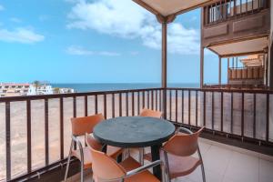 a table and chairs on a balcony with the beach at Appartment Zomero, SEAVIEW & WIFI & POOL in Costa Del Silencio