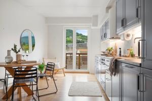 Una cocina con gabinetes blancos y una mesa y sillas. en Large 3 bedroom apartment in the center with parking, en Vossevangen 4 fotos más