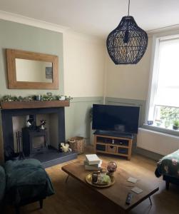 a living room with a fireplace and a tv at Old Store Cottage, Up Holland in Upholland